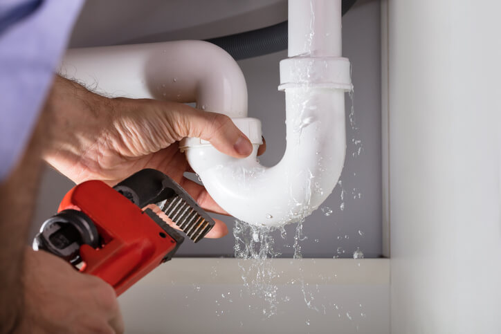 Plumber fixing leaky pipe