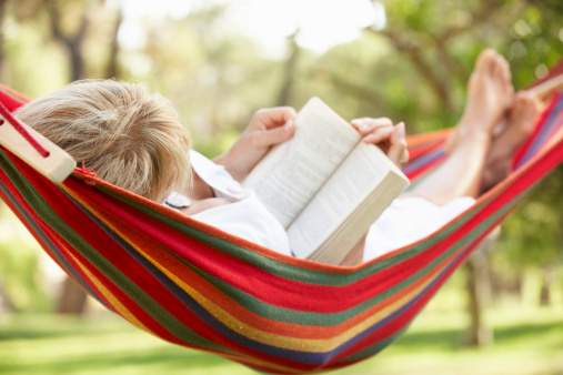 Woman Relaxing In Hammock With Book